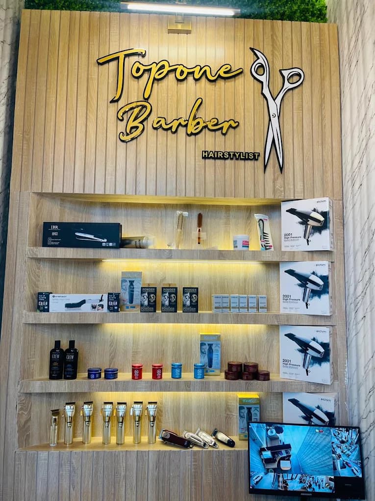 Topone Barber Hairstylist wall sign above backlit shelving stocked with grooming products